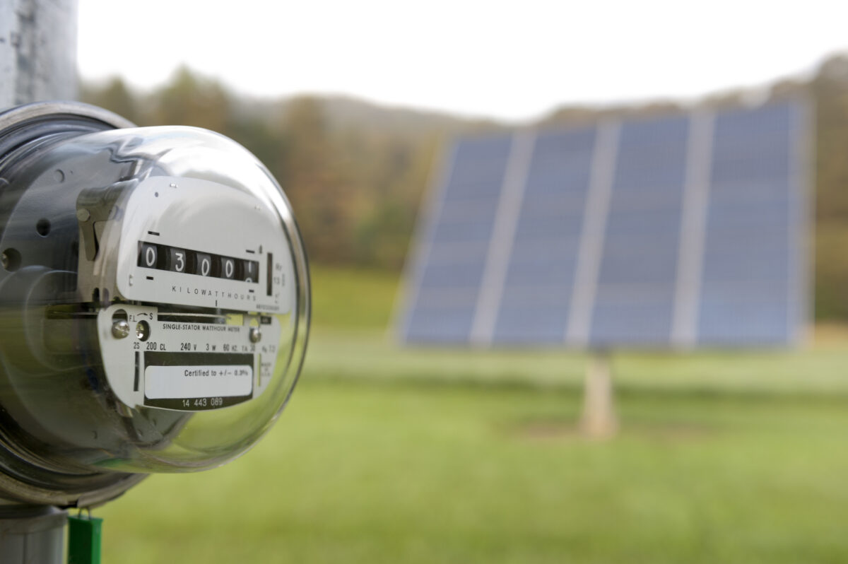 Stromzähler vor einer Solaranlage auf einer Wiese